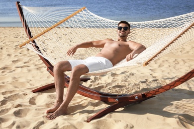 Photo of Young man relaxing in hammock on beach