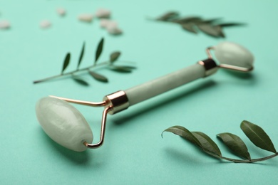 Photo of Natural face roller and leaves on turquoise background