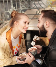 Lovely young couple enjoying tasty coffee at table outdoors