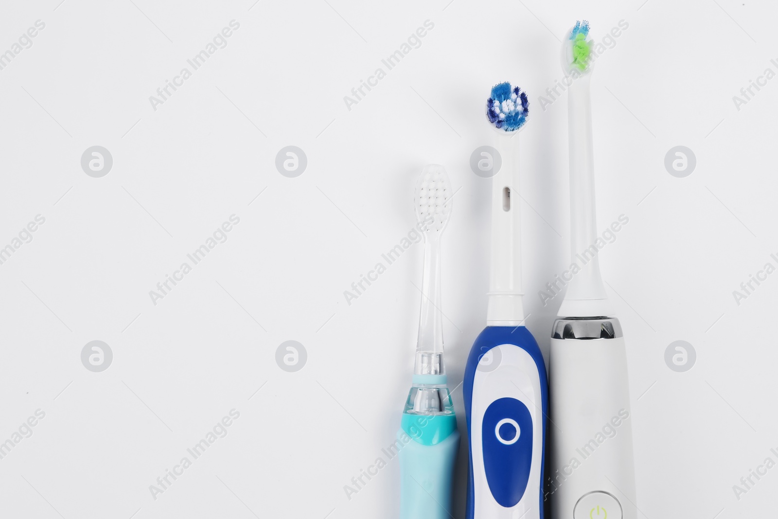 Photo of Electric toothbrushes on white background, flat lay. Space for text