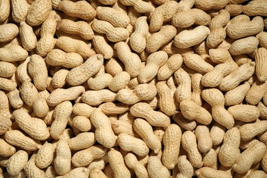 Photo of Many fresh unpeeled peanuts as background, top view