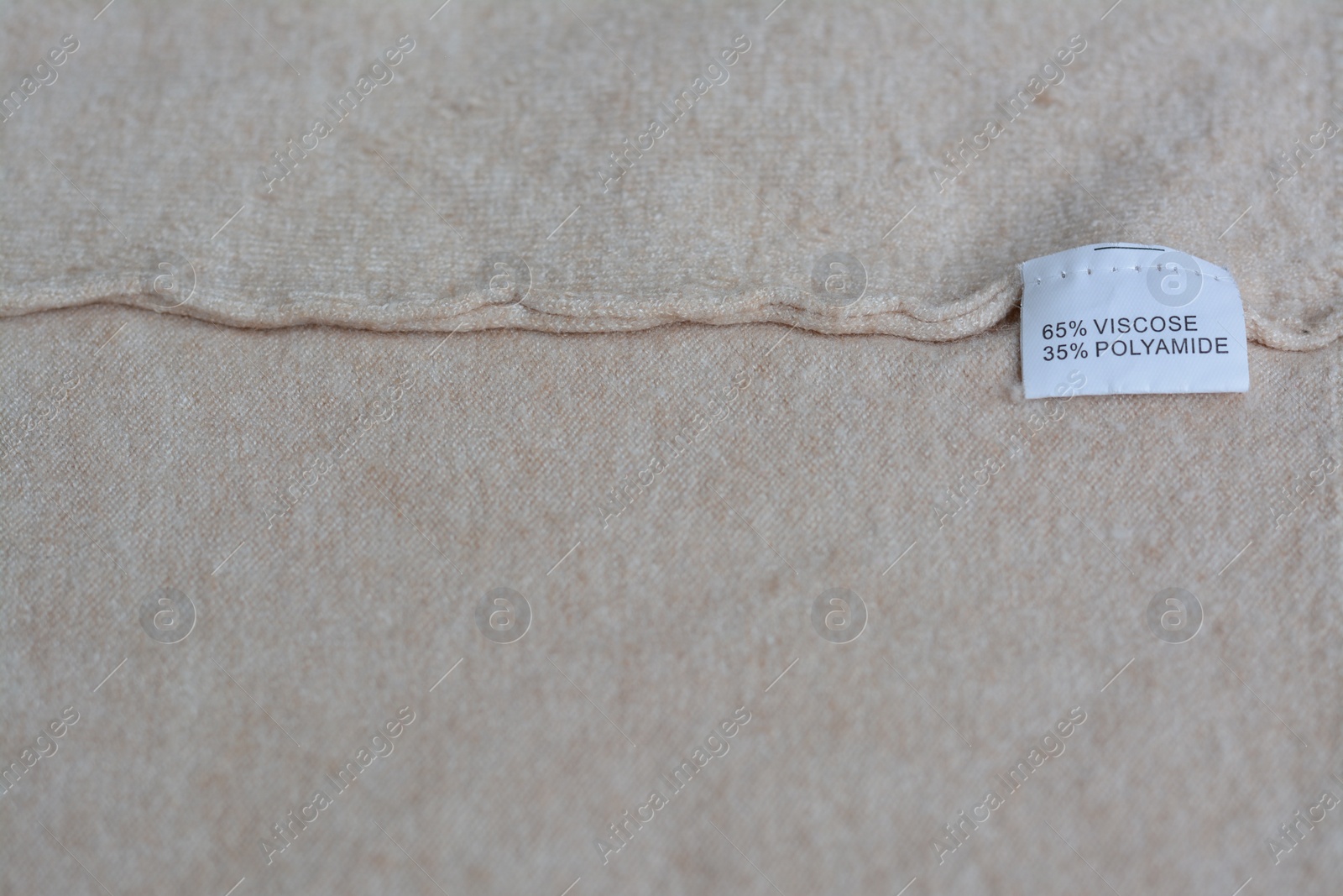 Photo of White clothing label with care information on beige garment, space for text