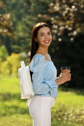 Beautiful young woman with stylish white backpack and coffee in park