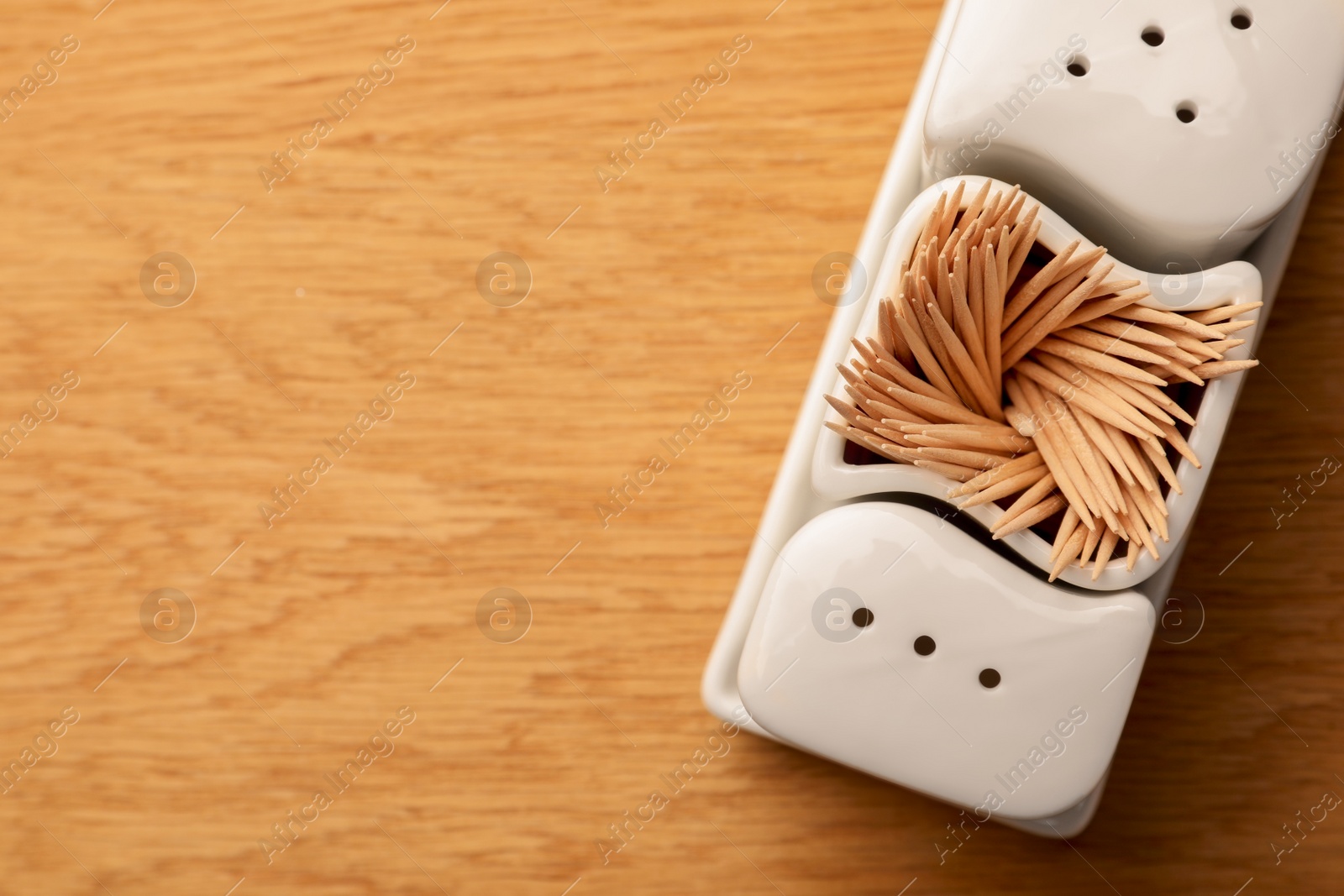 Photo of Holder with salt, pepper and toothpicks on wooden table, top view. Space for text