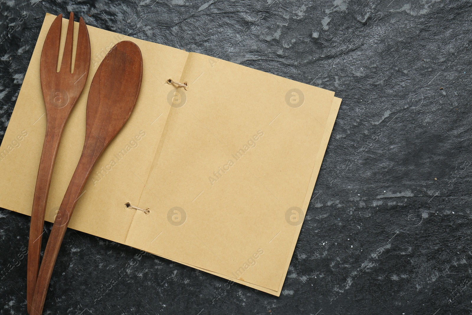 Photo of Blank recipe book and wooden utensils on black textured table, flat lay. Space for text