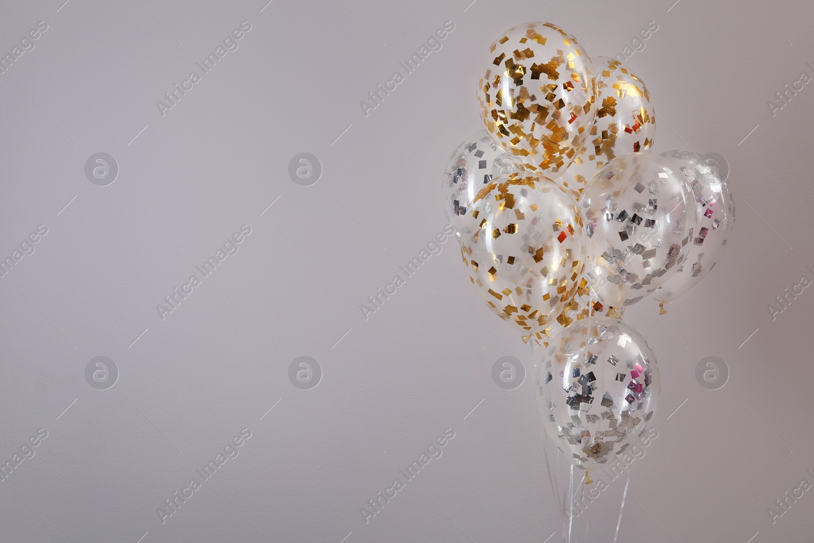 Photo of Bunch of bright balloons on grey background. Space for text