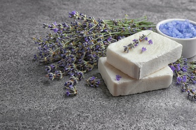 Photo of Hand made soap bars with lavender flowers on grey stone table, space for text