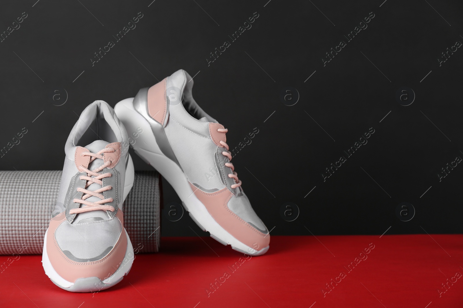 Photo of Composition of modern woman training shoes and mat on table. Space for text