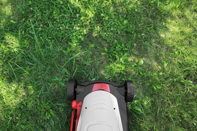 Photo of Cutting green grass with lawn mower in garden, top view. Space for text
