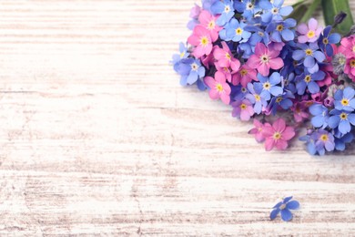 Photo of Beautiful blue and pink Forget-me-not flowers on white wooden table, above view. Space for text