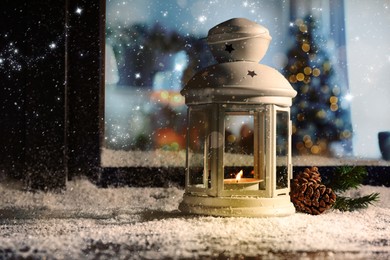 Image of Lantern with candle, fir branch and pine cones near window outdoors. Christmas eve
