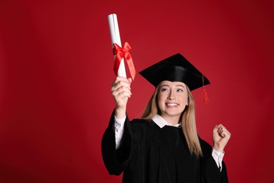 Happy student with diploma on red background