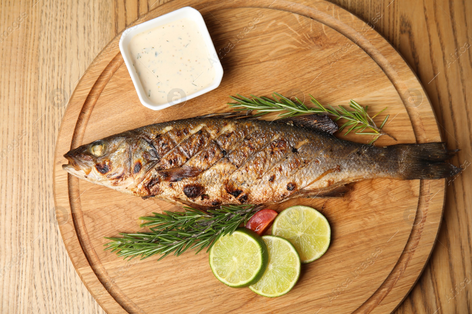 Photo of Delicious grilled fish served on wooden table, top view