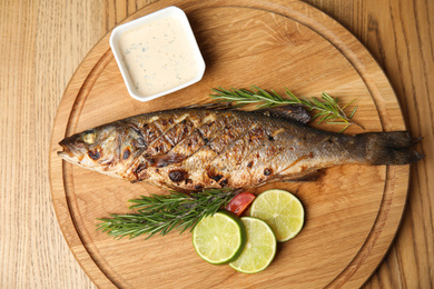 Photo of Delicious grilled fish served on wooden table, top view