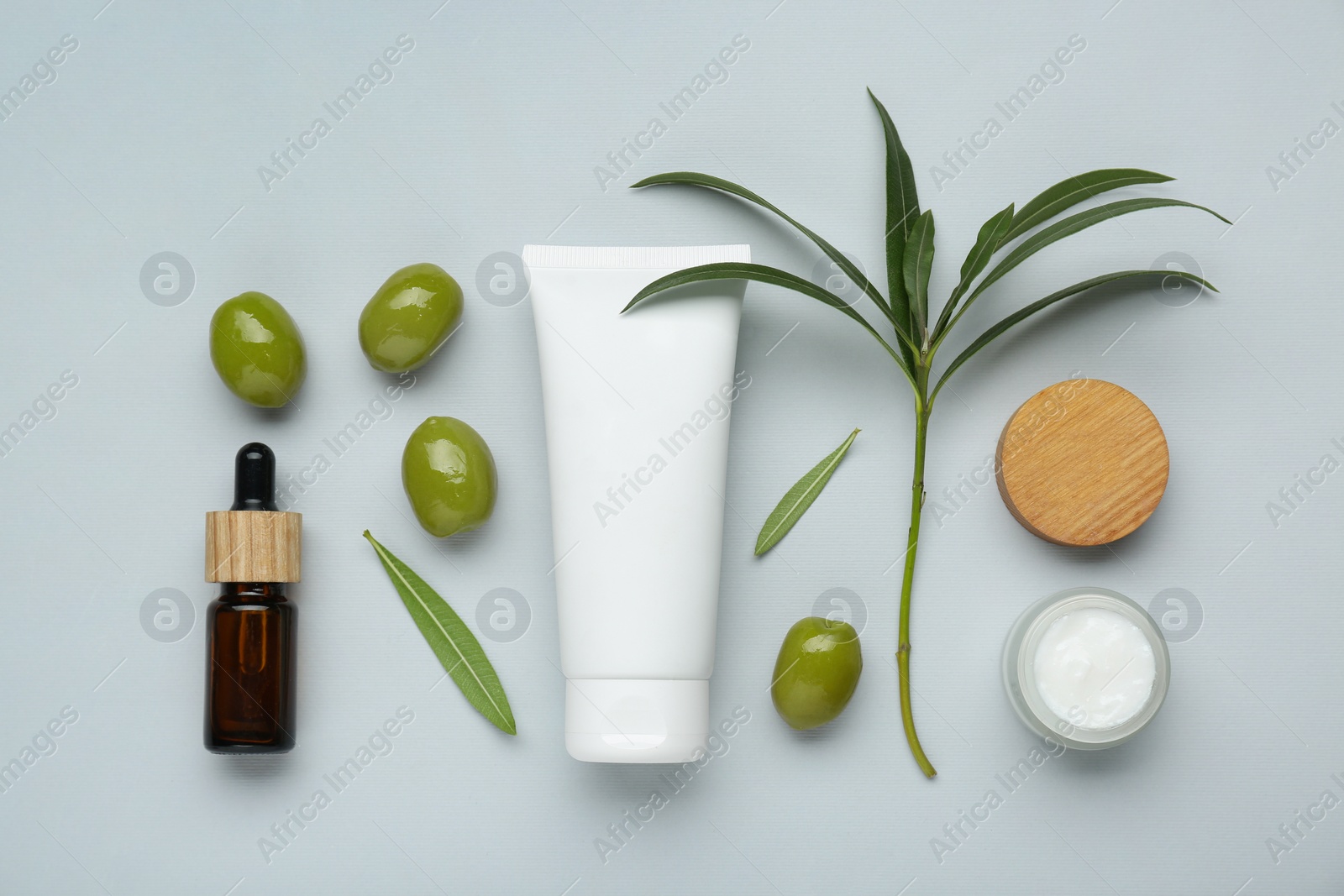 Photo of Cosmetic products with olive essential oil on light grey background, flat lay