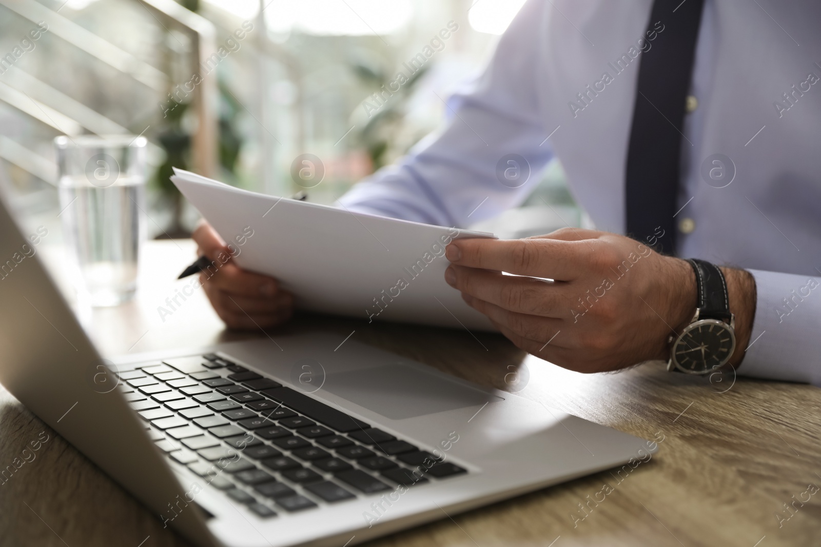 Photo of Businessman working with documents at wooden desk in office, closeup