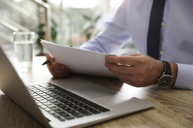 Businessman working with documents at wooden desk in office, closeup