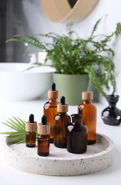 Photo of Tray with bottles of essential oils on white table in bathroom