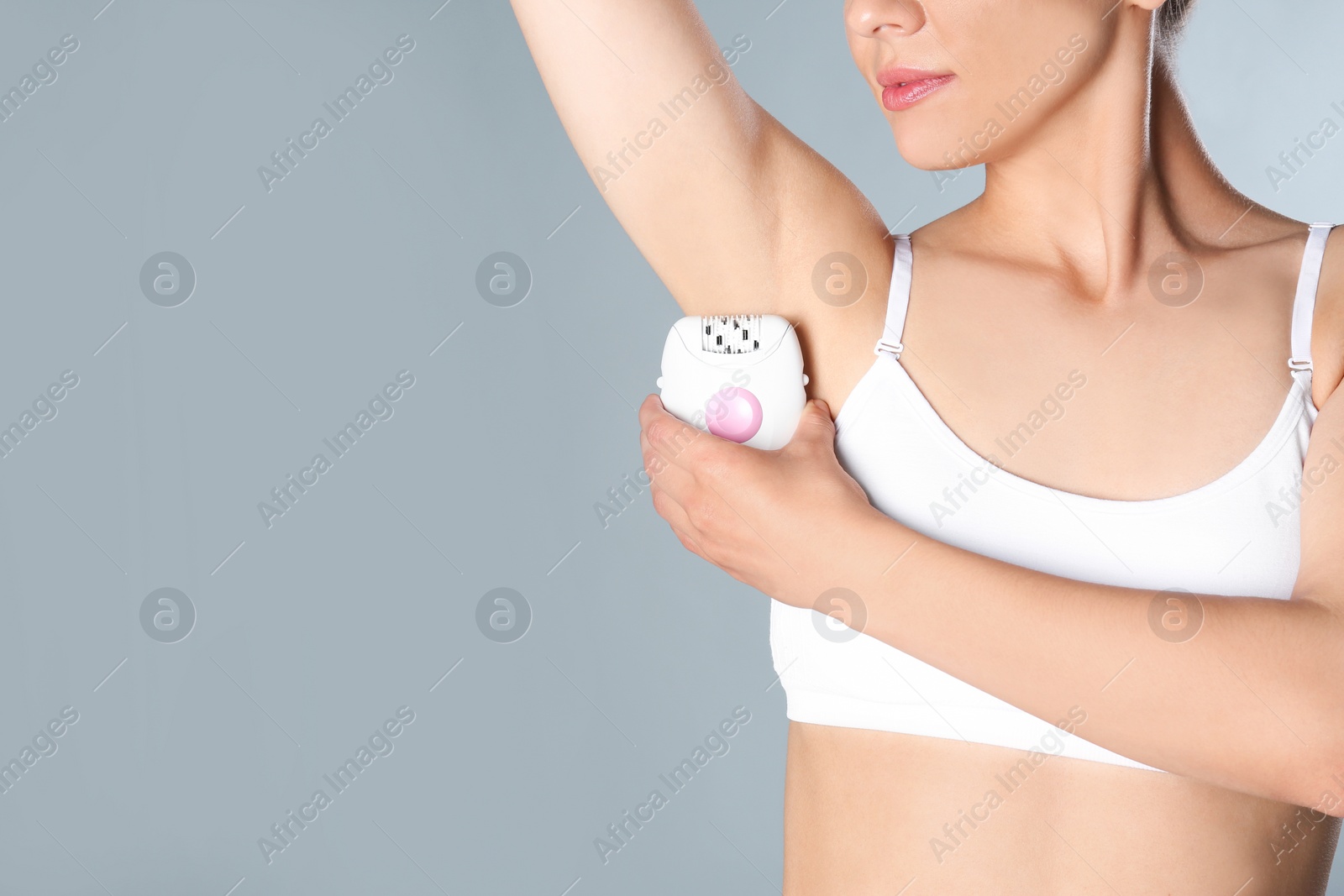 Photo of Woman doing armpit epilation procedure on grey background, closeup. Space for text