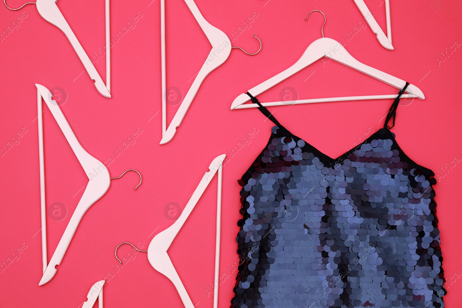 Photo of Women's garment and hangers on pink background, flat lay. Clothes rent concept
