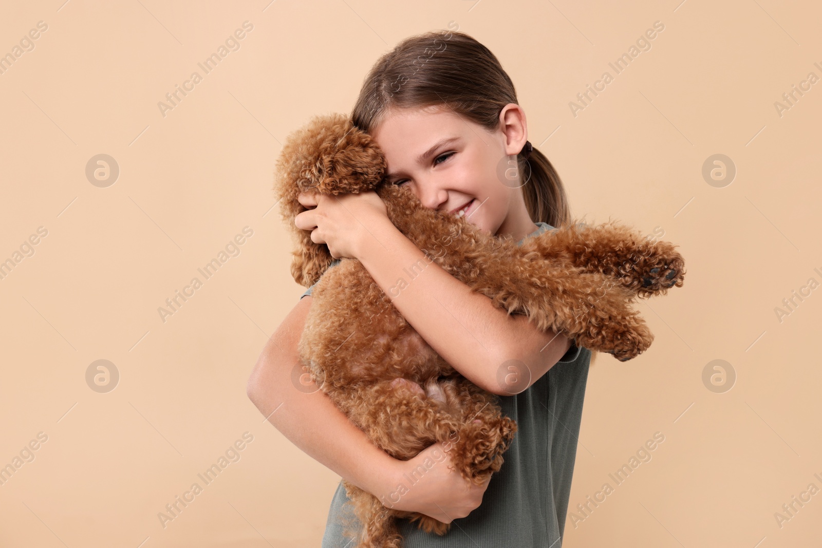 Photo of Little child with cute puppy on beige background. Lovely pet