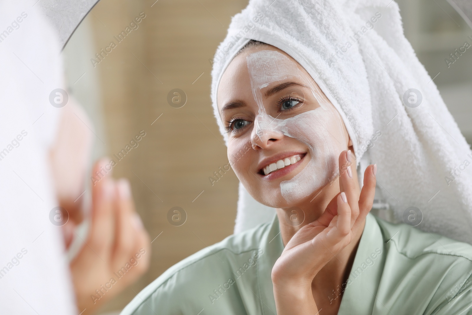 Photo of Woman with face mask in front of mirror indoors. Spa treatments