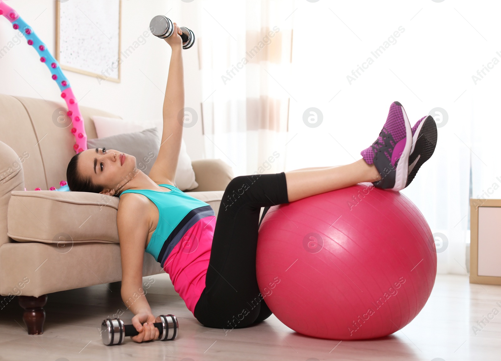 Photo of Lazy young woman with sport equipment at home