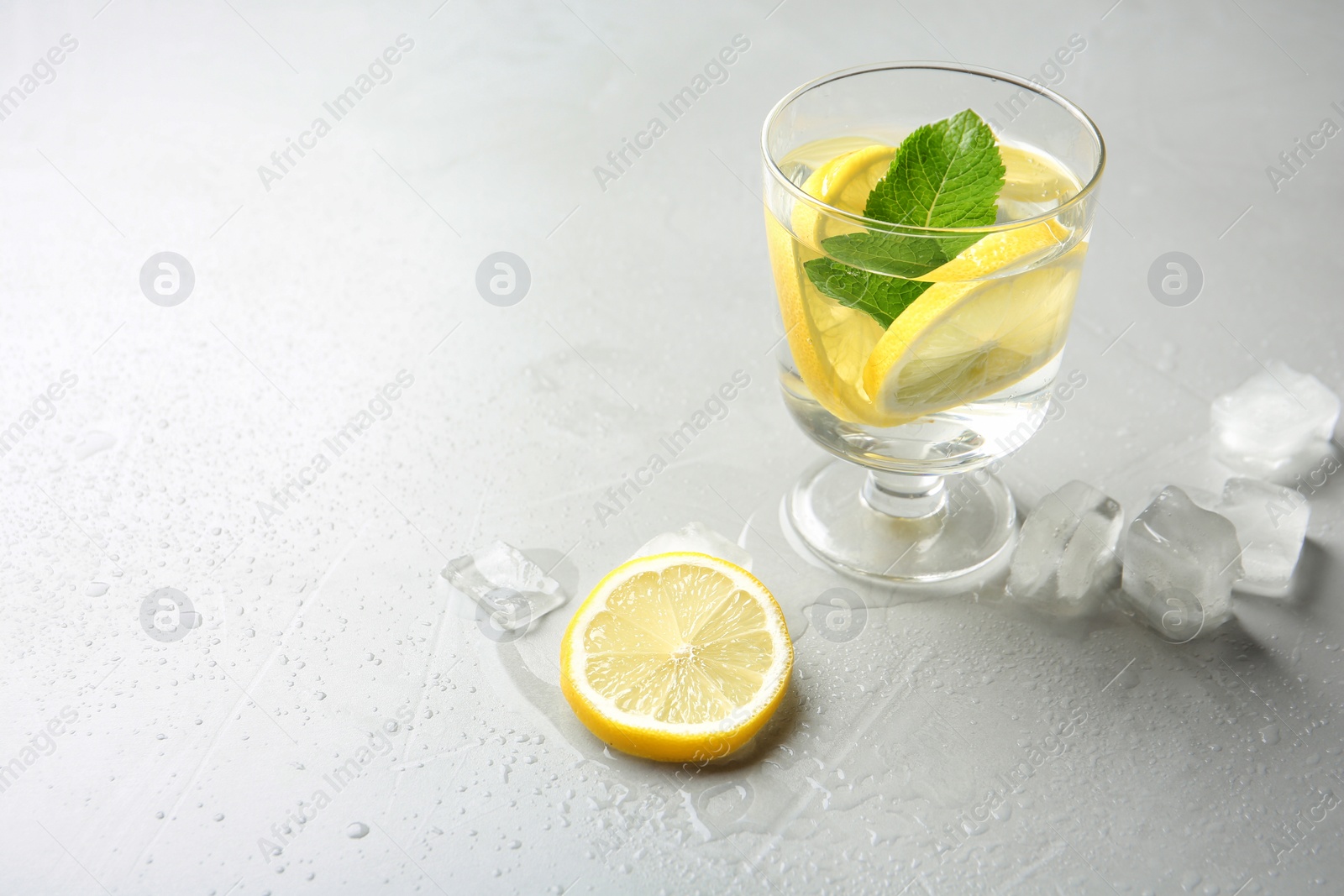 Photo of Glass with lemon water and ice cubes on table