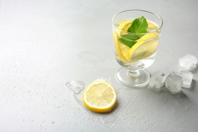 Glass with lemon water and ice cubes on table