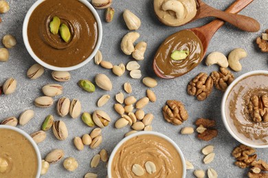 Photo of Tasty nut butters and raw nuts on light grey table, flat lay