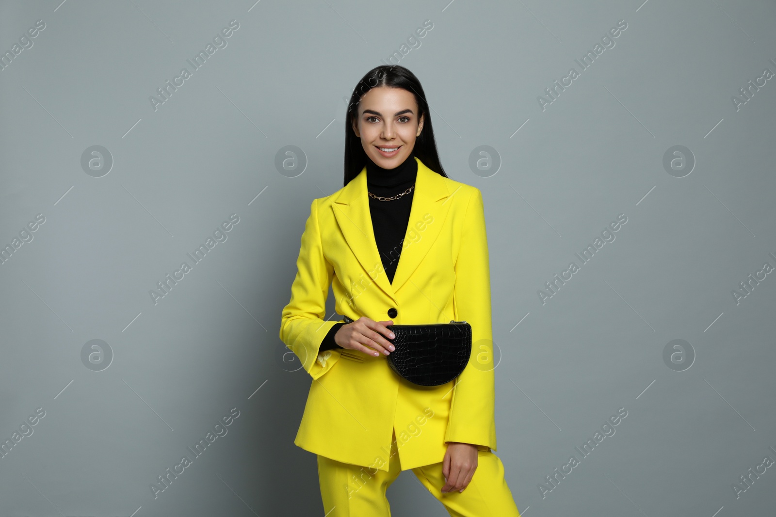 Photo of Beautiful young woman with stylish waist bag on grey background