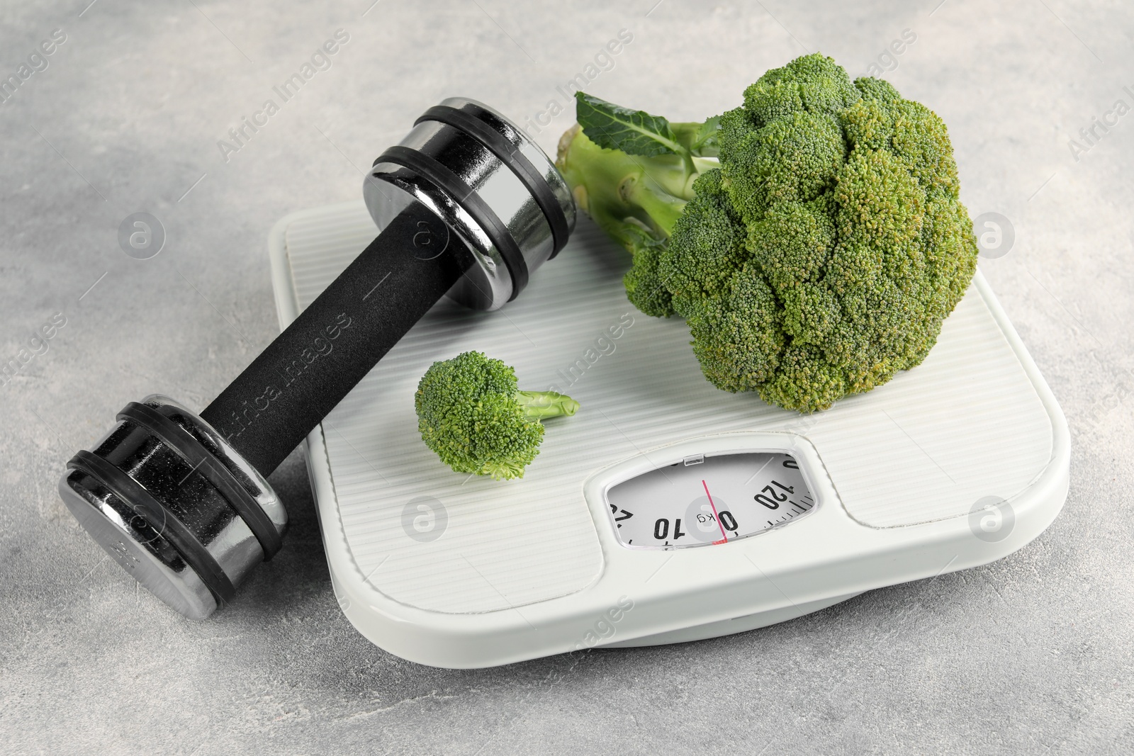 Photo of Healthy diet. Scale, broccoli and dumbbell on grey table