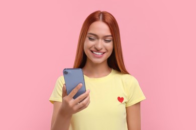 Photo of Beautiful happy woman using smartphone on pink background