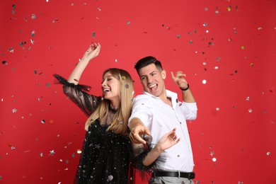 Photo of Happy couple and confetti on red background