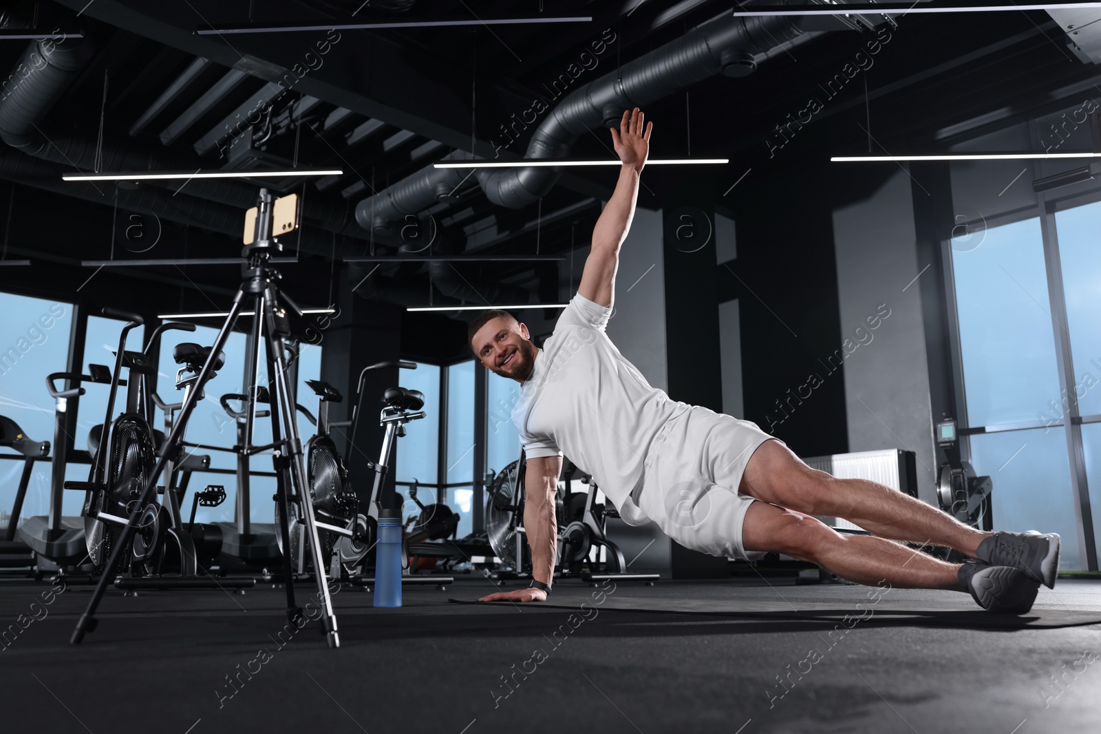 Photo of Trainer streaming online workout with phone at gym