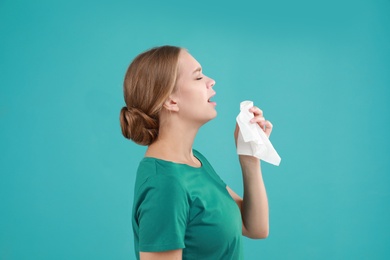 Young woman suffering from allergy on turquoise background