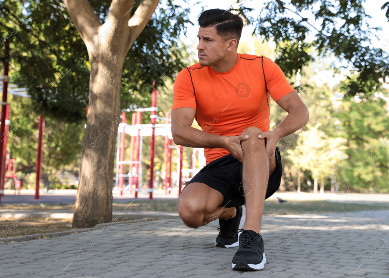 Photo of Man in sportswear having knee problems on sports ground