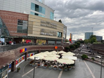 Photo of WARSAW, POLAND - JULY 17, 2022: View of big shopping mall with customers under cloudy sky