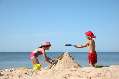 Cute little children playing with plastic toys on sandy beach