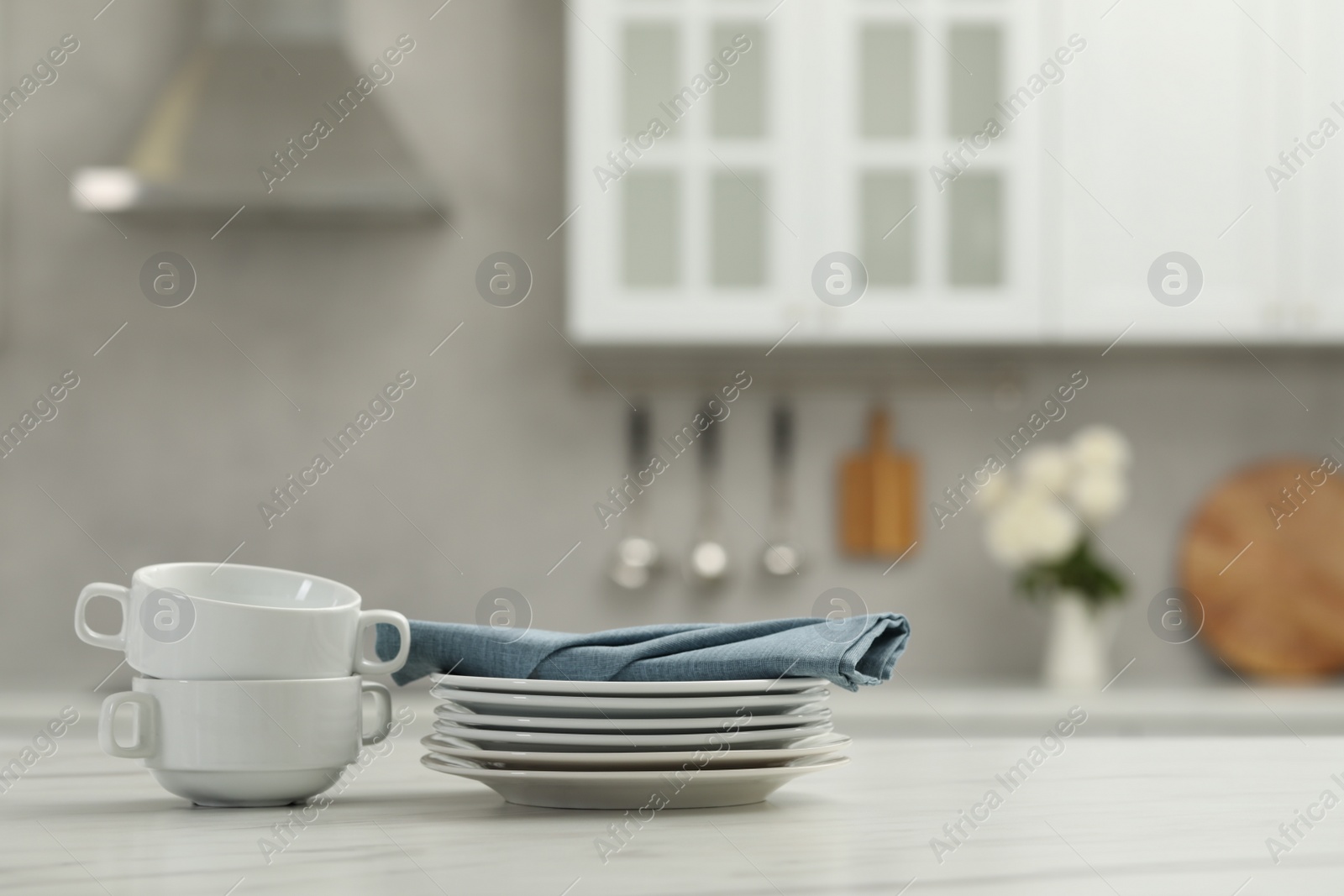 Photo of Clean dishware on white table in kitchen, space for text