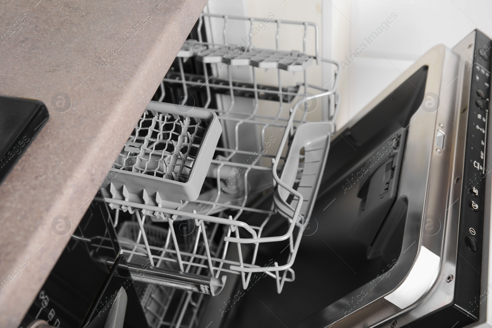 Photo of Open clean empty dishwasher in kitchen, closeup