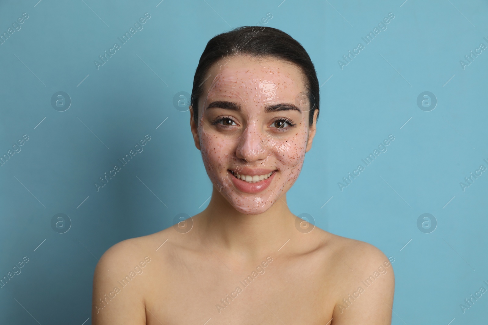 Photo of Woman with pomegranate face mask on light blue background