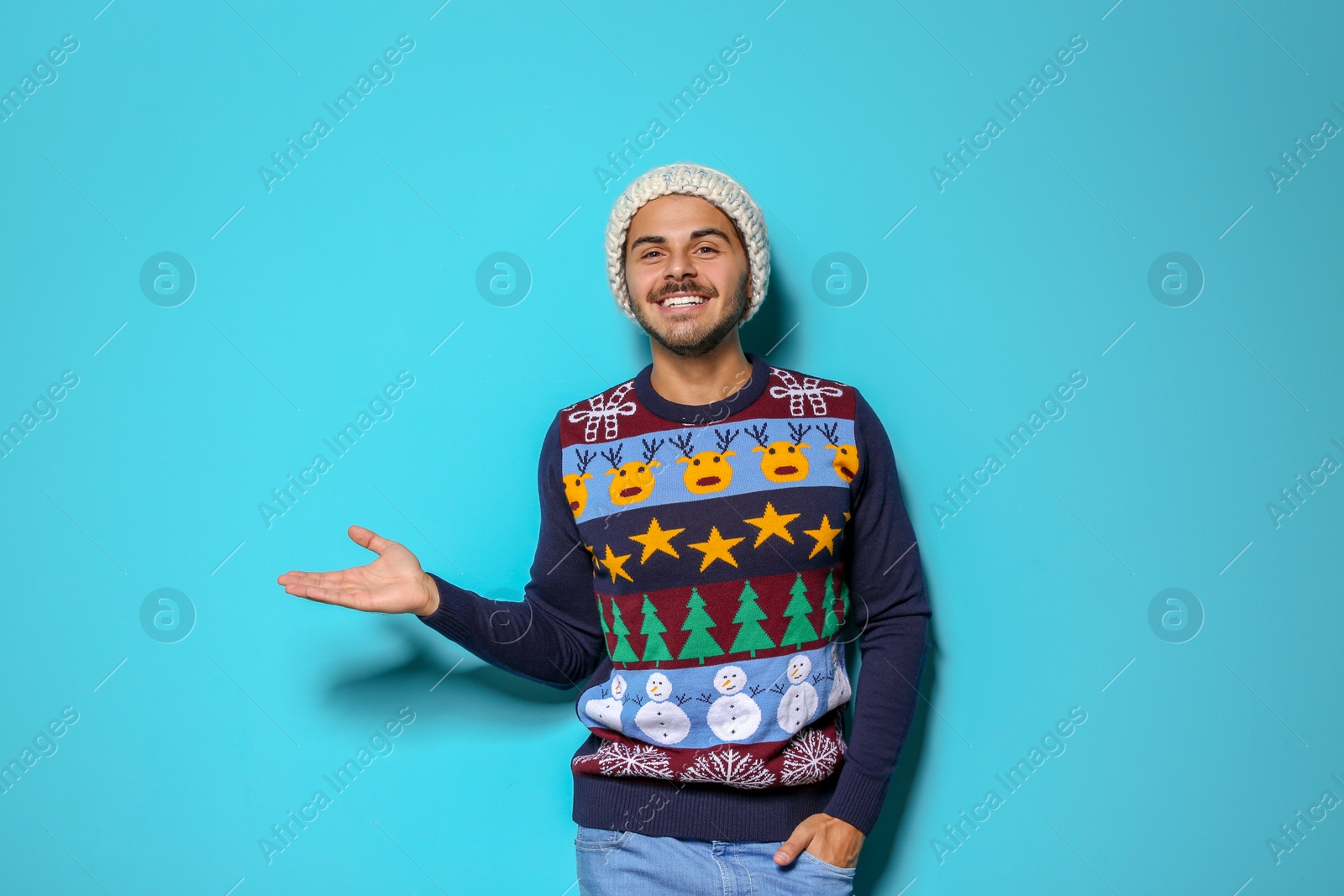 Photo of Young man in Christmas sweater and knitted hat on color background