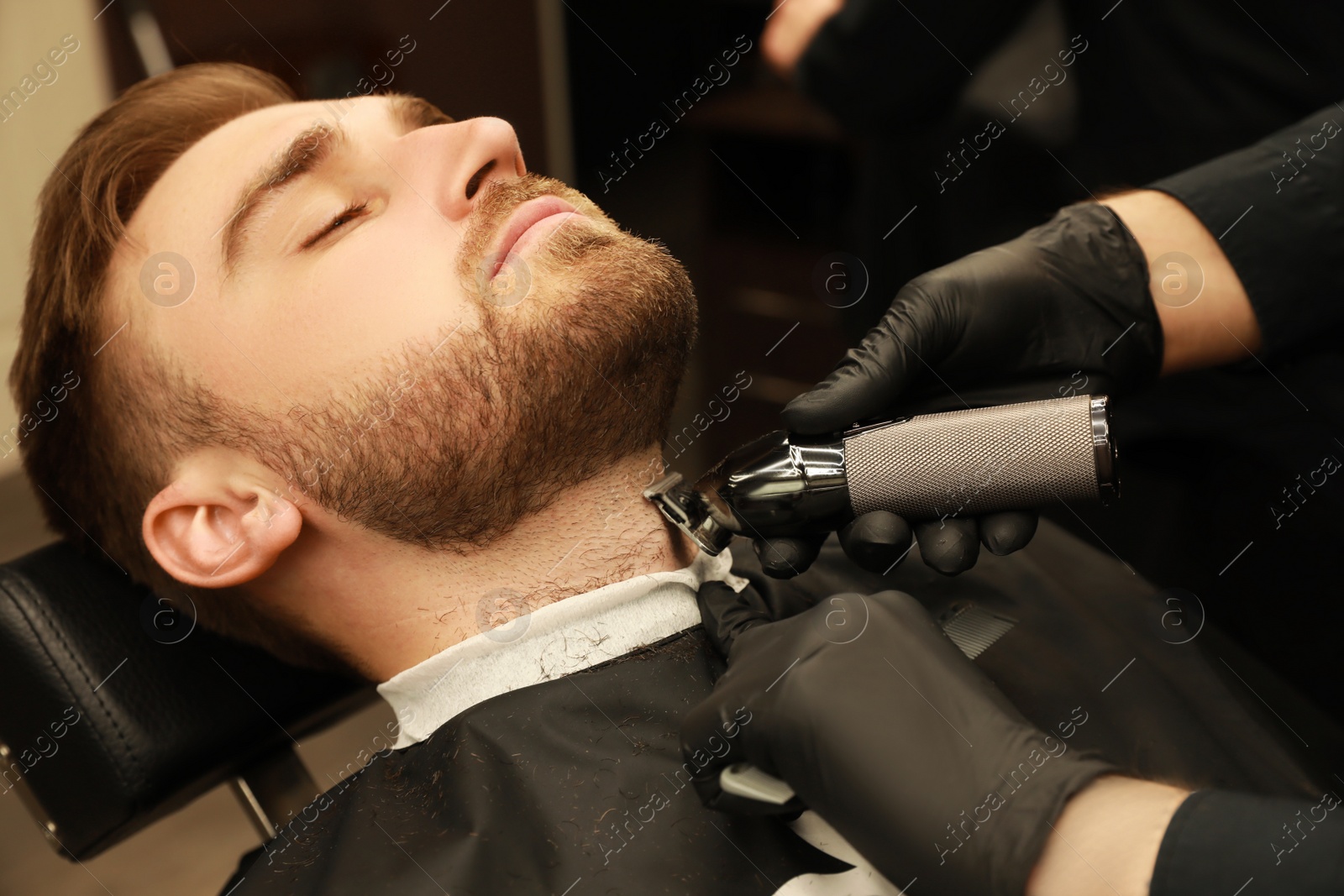 Photo of Professional hairdresser working with client in barbershop