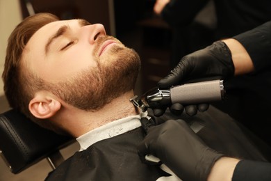 Professional hairdresser working with client in barbershop