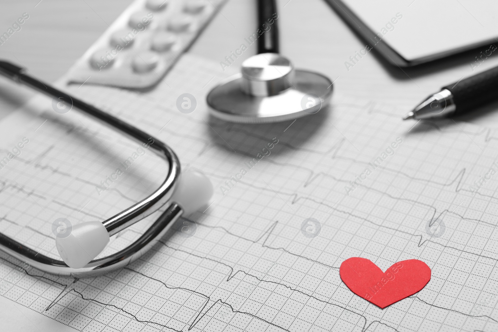 Photo of Cardiogram report, red paper heart and stethoscope on table, closeup