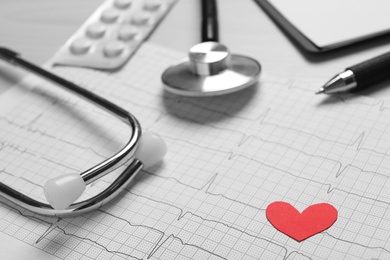 Photo of Cardiogram report, red paper heart and stethoscope on table, closeup