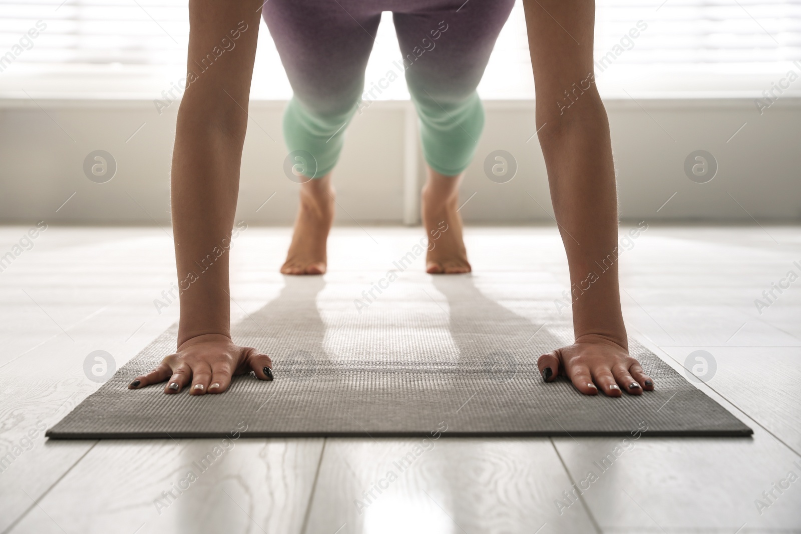 Photo of Woman practicing plank asana in yoga studio, closeup. Phalankasana pose