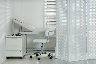 Examination room with modern couch and folding screen in clinic