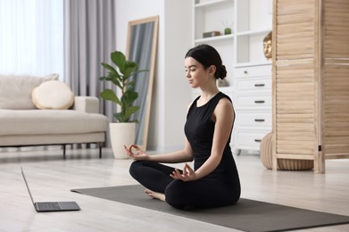 Photo of Beautiful girl having yoga class with online couch at home